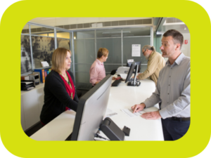 Mennesker foran og bak en betjent skranke